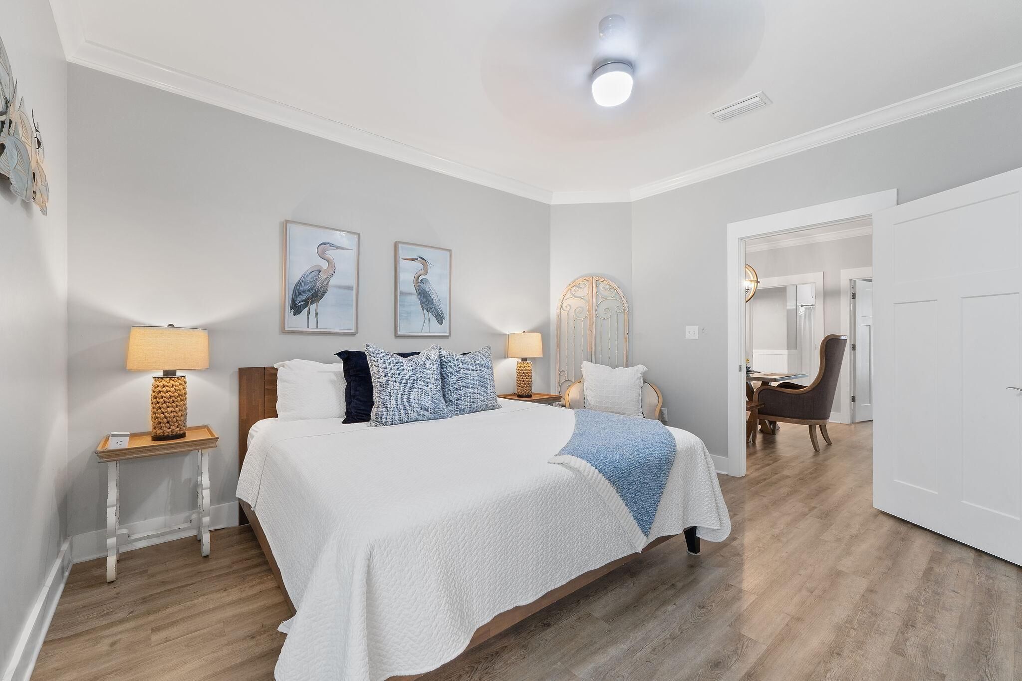 A bedroom with a bed, two bedside tables, a nightstand, a mirror, and a door leading to another room.