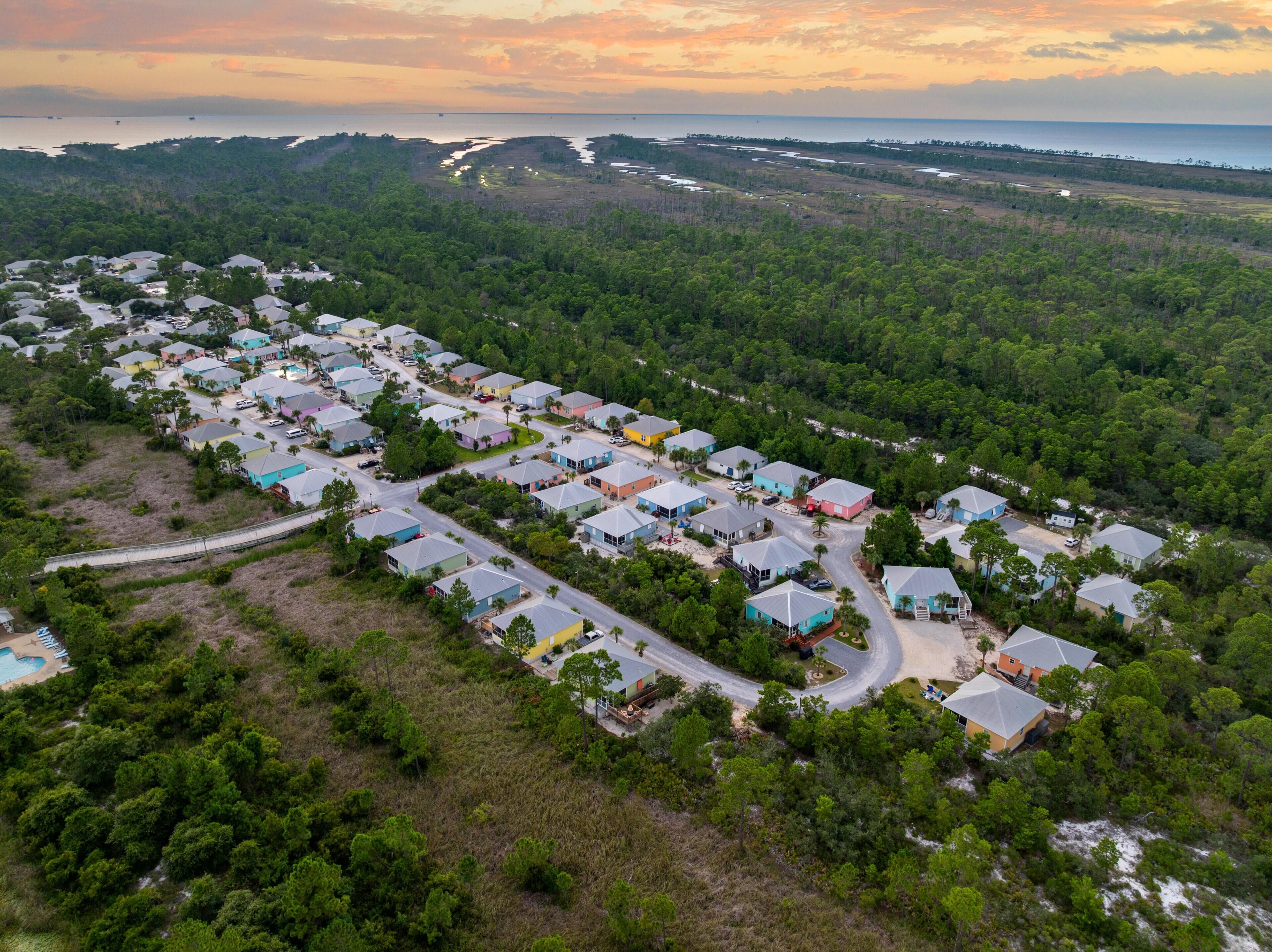 An aerial view of a residential area with houses, roads, and a body of water in the background.