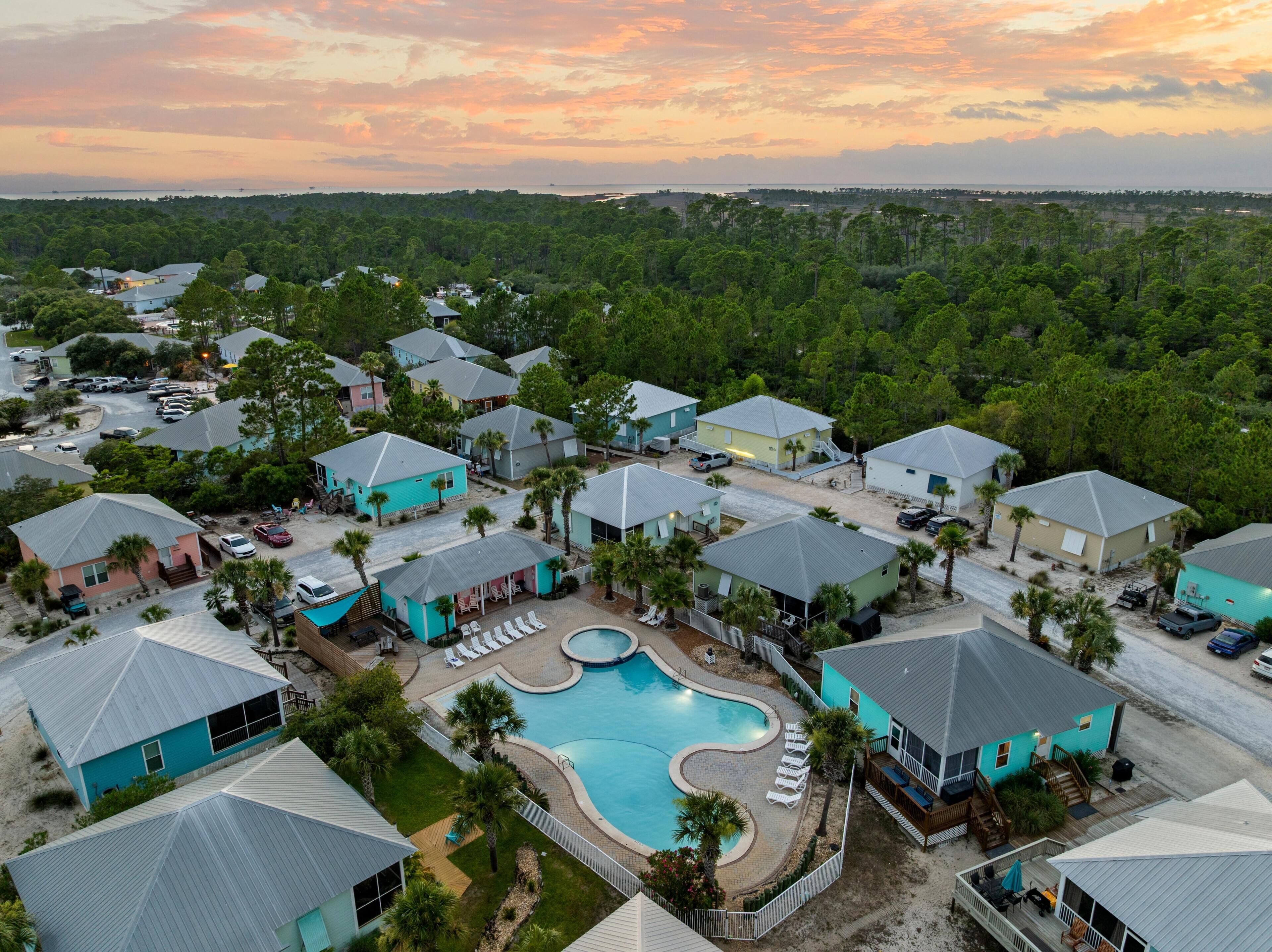 A residential area with houses, a swimming pool, and a view of the ocean at sunset.
