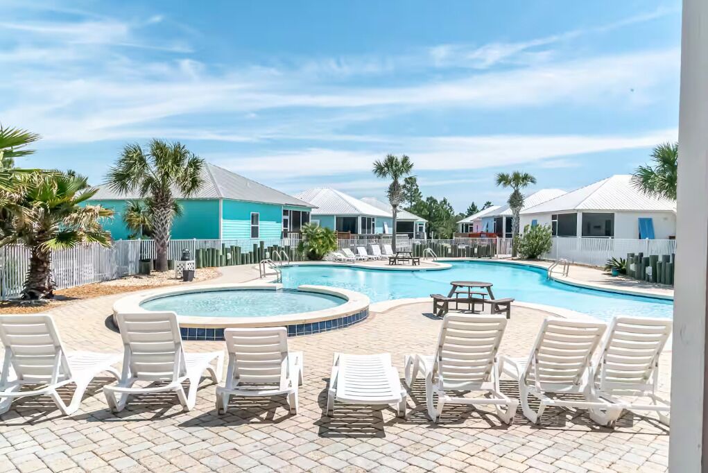 A pool area with lounge chairs, a small pool, and a building with a blue roof.