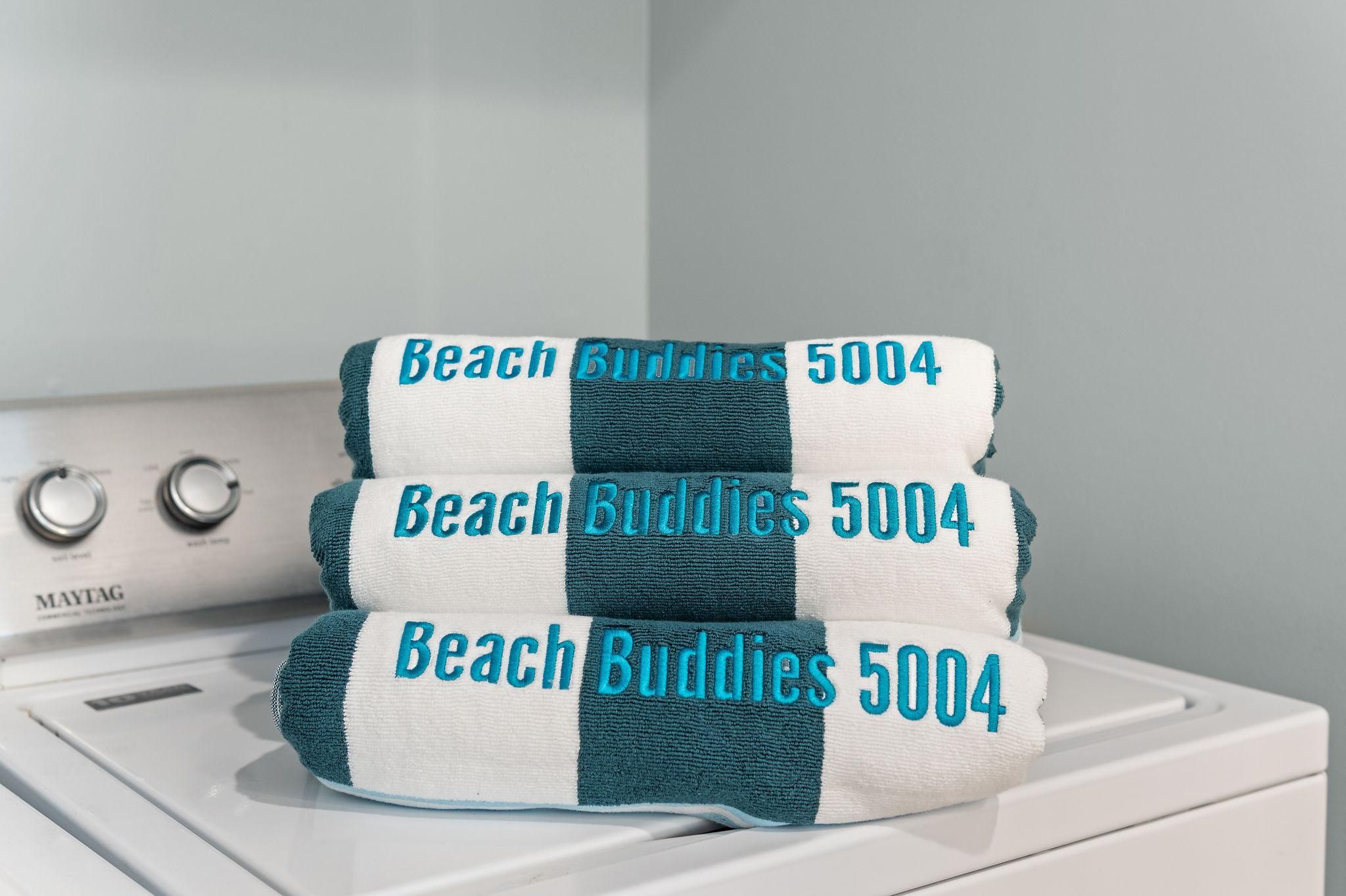 Een stapel handdoeken met de tekst 'Beach Buddies 5004' op een wasmachine.