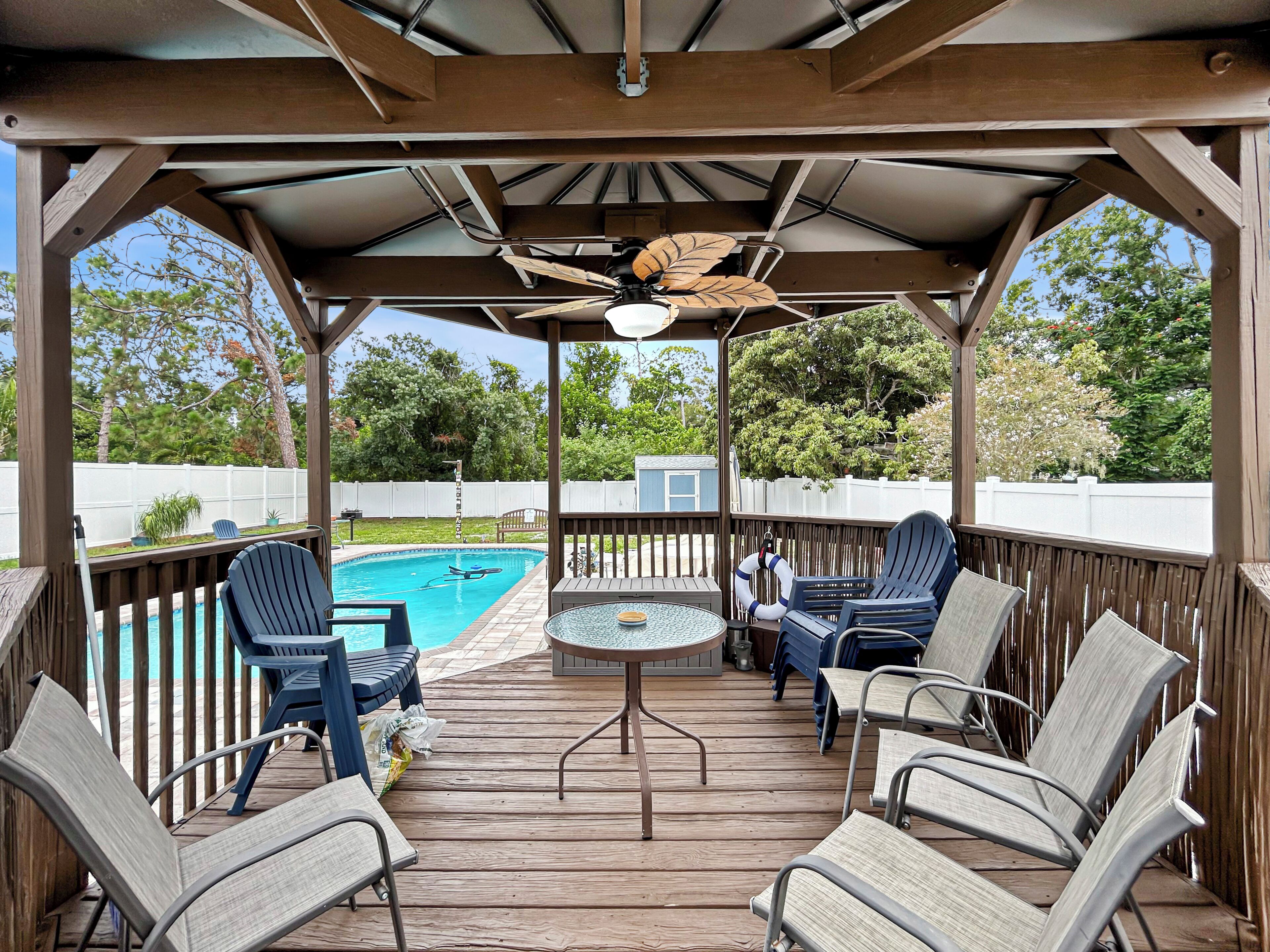 A covered outdoor deck with a pool, lounge chairs, and a table.