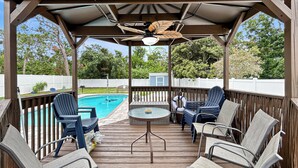A covered outdoor deck with a pool, lounge chairs, and a table. - Azure Bungalow: Pool, Gazebo, & Beach Vibes, A/C, 15 mins from Anna Maria Island (Bradenton)