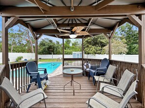 Eine überdachte Terrasse im Freien mit Pool, Liegestühlen und einem Tisch.