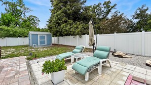 A backyard patio with outdoor furniture, a small shed, and a white fence. - Azure Bungalow: Pool, Gazebo, & Beach Vibes, A/C, 15 mins from Anna Maria Island (Bradenton)