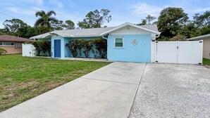 A single-story house with a blue exterior, a front door, and a small window. - Azure Bungalow: Pool, Gazebo, & Beach Vibes, A/C, 15 mins from Anna Maria Island (Bradenton)