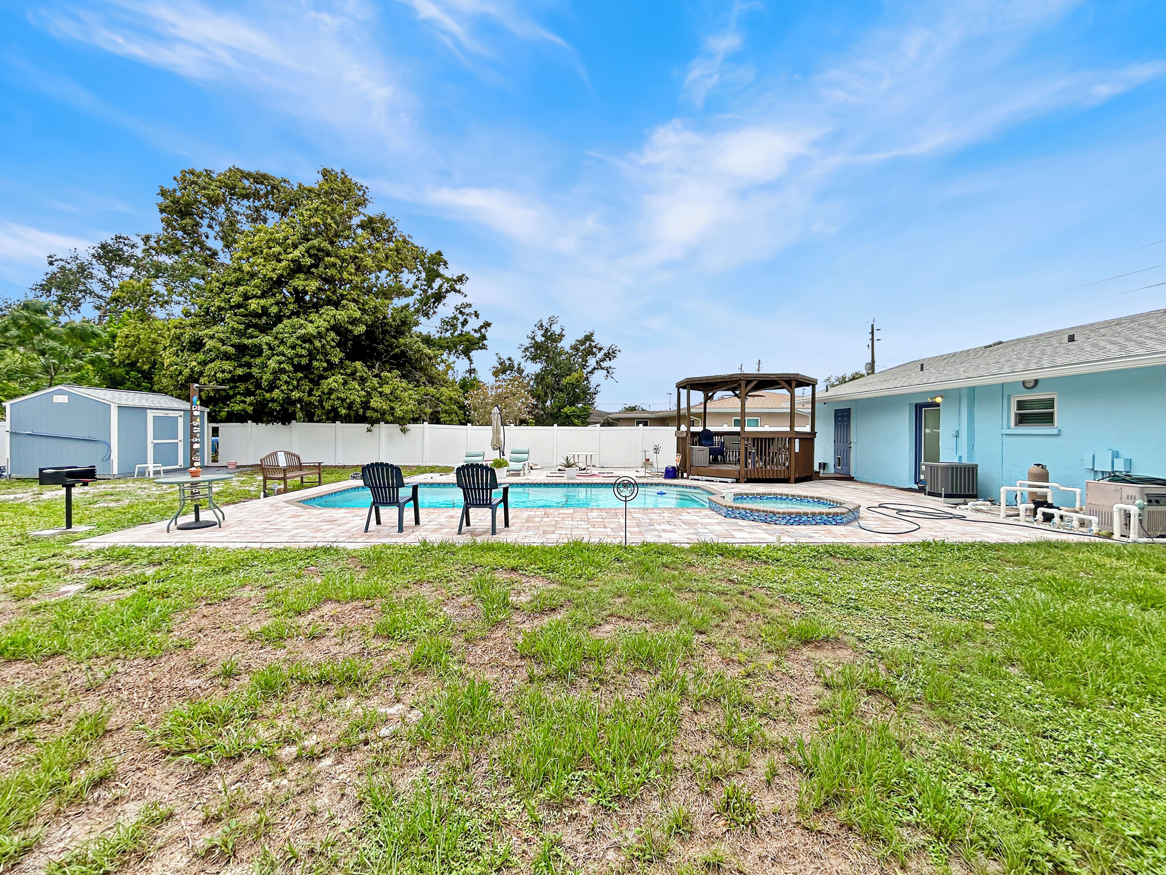 A backyard with a swimming pool, a gazebo, and a small shed.