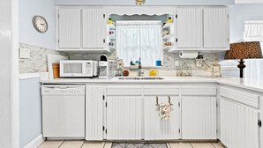 A kitchen with white cabinets, a microwave, a coffee maker, and a clock on the wall. - Azure Bungalow: Pool, Gazebo, & Beach Vibes, A/C, 15 mins from Anna Maria Island (Bradenton)