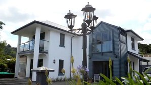 A two-story house with a balcony, a garage, and a street lamp. - Spacious Villa in the Heart of Akaroa (Akaroa)