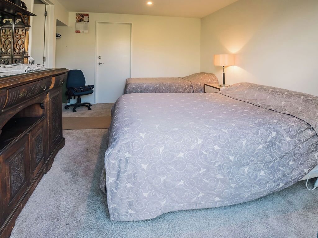 A bedroom with a large bed, a desk with a lamp, and a chair.