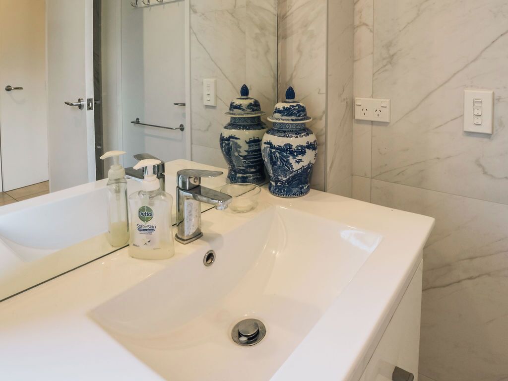 A bathroom with a white sink, a mirror, and two blue ceramic vases.