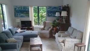 A living room with a sofa set, a coffee table, a TV, and a painting on the wall. - Spacious Villa in the Heart of Akaroa (Akaroa)