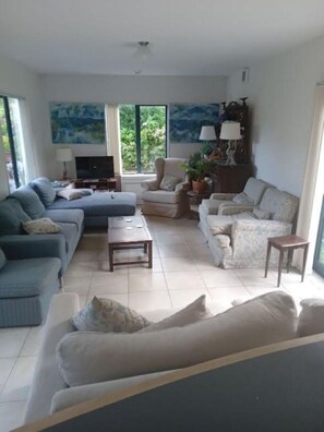 A living room with a sofa set, a coffee table, a TV, and a painting on the wall. - Spacious Villa in the Heart of Akaroa (Akaroa)