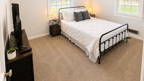 A bedroom with a bed, bedside tables, a television, and a window. - Olivet Cottage, Sleeps 14, Family Friendly Retreat Minutes from Paducah (Paducah)