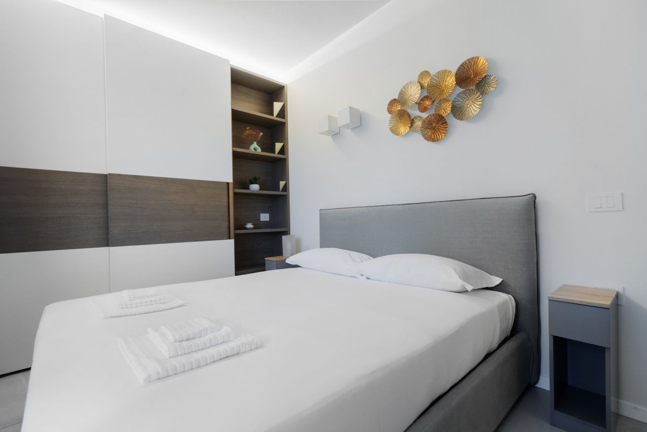 Een moderne slaapkamer met een groot bed, een inbouwkast en decoratieve muurkunst.