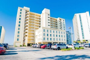 A multi-story hotel with a central building and several parking spaces in front. - Boardwalk 486 (Gulf Shores)