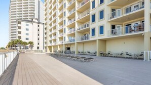 A multi-story hotel with balconies, a covered outdoor seating area, and a wooden deck. - Boardwalk 486 (Gulf Shores)