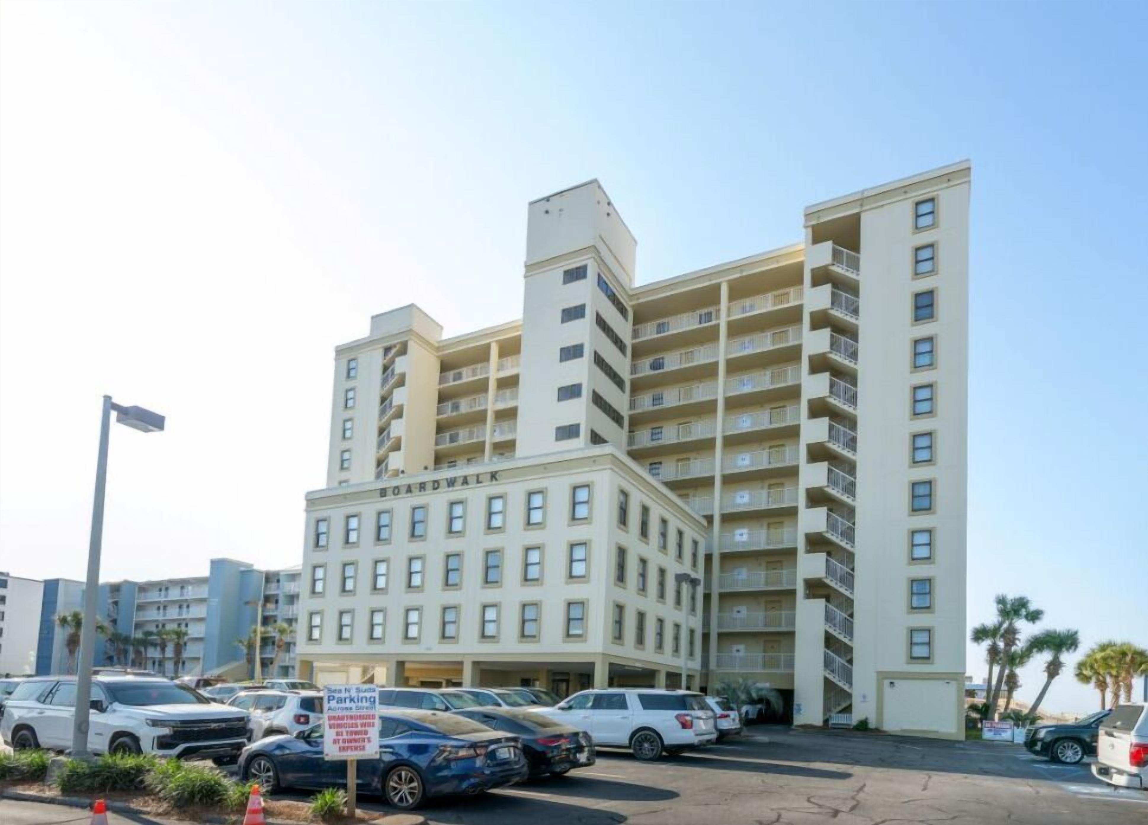 A multi-story hotel with a parking lot in front.