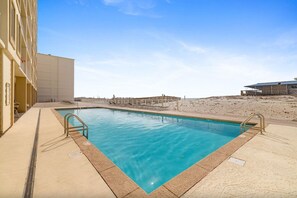 A rectangular swimming pool with a clear blue water surface, surrounded by a concrete deck with metal railings. - Boardwalk 486 (Gulf Shores)