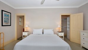 Une chambre à coucher avec un grand lit, deux tables de chevet avec des lampes, une armoire et un tableau encadré au mur.