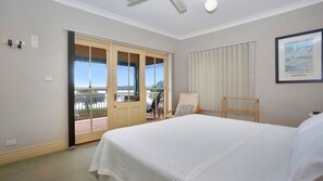 A hotel room with a bed, a chair, a balcony with a view, and a framed picture on the wall. - Rivers Edge Apartment (Tea Gardens)