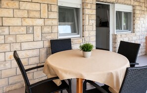 A round table with a beige tablecloth, surrounded by four black chairs, set against a stone wall with two windows. - Awesome apartment in Vir with WiFi (Vir)