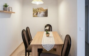 A dining area with a wooden table, four chairs, a potted plant, a framed picture, and a pendant light. - Awesome apartment in Vir with WiFi (Vir)