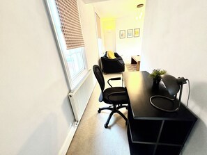 A room with a black desk, two black office chairs, a radiator, a window with blinds, and a wall with framed pictures. - Spacious Townhouse central Leamington with parking (Royal Leamington Spa)