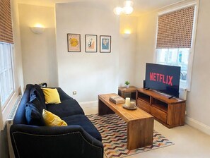 Un salon avec un canapé, une table basse, un téléviseur et des œuvres d’art murales.