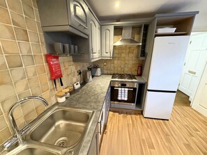 A compact kitchen with a sink, stove, oven, and white cabinets. - Spacious Townhouse central Leamington with parking (Royal Leamington Spa)