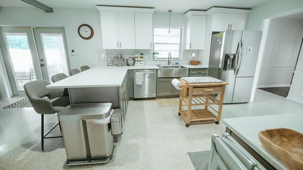 A modern kitchen with white cabinets, stainless steel appliances, and a central island with seating. - Wayfarer Basecamp-Centrally located. RC track! (Orlando)