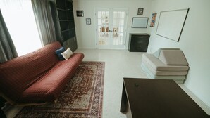 A living room with a red sofa, a beige sofa, a dark wooden coffee table, and a patterned rug. - Wayfarer Basecamp-Centrally located. RC track! (Orlando)