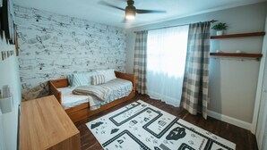A room with a bed, a ceiling fan, a window with curtains, a wall with a pattern, and a rug. - Wayfarer Basecamp-Centrally located. RC track! (Orlando)