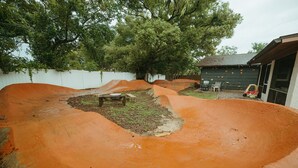 A dirt track with a bench and a small table, surrounded by a white fence and trees. - Wayfarer Basecamp-Centrally located. RC track! (Orlando)