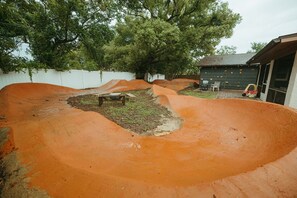 A dirt track with a bench and a small table, surrounded by a white fence and trees. - Wayfarer Basecamp-Centrally located. RC track! (Orlando)