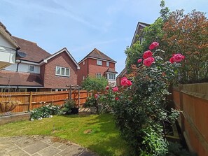 Un quartier résidentiel avec des maisons en briques, une clôture en bois et un jardin agrémenté de fleurs roses.