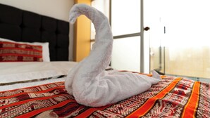 Una cama con una toalla en forma de cisne blanco sobre un edredón estampado.