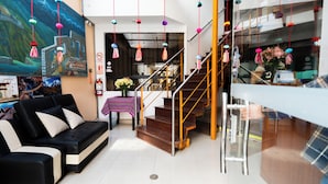 Un vestíbulo de hotel con un sofá, una escalera, un extintor y un calendario en la pared.