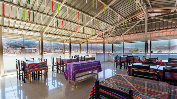 Un espacio amplio con ventanas grandes, mesas con manteles de colores y sillas dispuestas para comer.
