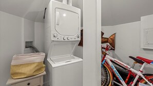 A laundry area with a washing machine, a drying rack, and a bicycle.