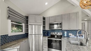 A modern kitchen with grey cabinets, a stainless steel refrigerator, a built-in oven, and a microwave.