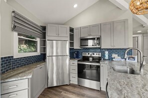 Una cocina moderna con armarios grises, un refrigerador de acero inoxidable, un horno empotrado y un microondas.