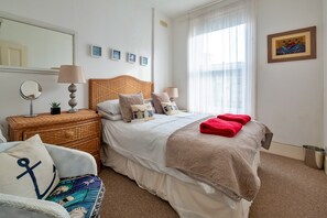 A neatly arranged bedroom with a bed, bedside tables, a mirror, and a window with curtains. - Sea View Lyme Regis House for 9 (Ventnor)