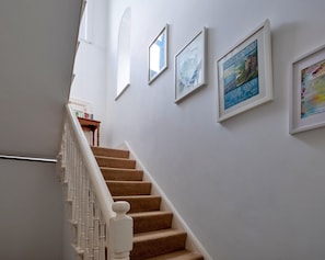 Eine Treppe mit weißer Handlauf und beigefarbenen Teppichstufen, die zu einer Zwischenebene führen.