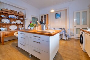 Eine Küche mit Holzausstattung, einer zentralen Kochinsel und einem Essbereich mit Tisch und Stühlen.