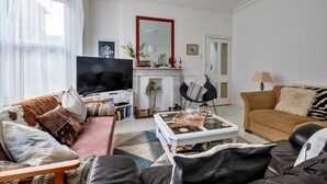 En stue med sofa, sofabord, fjernsyn og pejs.