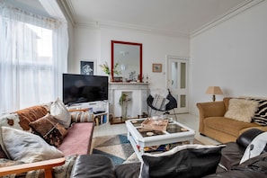 Ein Wohnzimmer mit einer Couch, einem Couchtisch, einem Fernseher und einem Kamin.