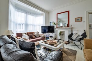 A living room with a sofa, armchair, coffee table, TV, fireplace, and a mirror.