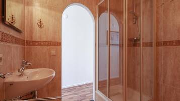 Baño con cabina de ducha de vidrio, lavabo y azulejos decorativos.