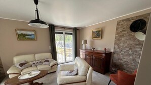 Una sala de estar con un sofá, un sillón y una mesa baja con una bandeja. Hay un aparador y una pared con textura.